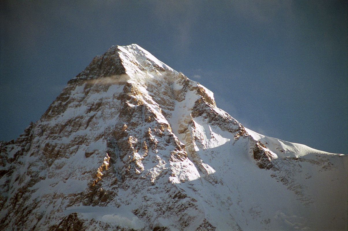 24 Sunrise On K2 Summit From Concordia The first rays of sunrise light up the K2 summit, the K2 South Face, the Great Serac, and the Shoulder, seen from Concordia. The upper part of the K2 South-South-West Ridge catches a bit of sun separating the west face in shadow from the sun descending the K2 South Face. On August 3, 1986 Wojciech Wroz, Przemyslaw Piasecki and Peter Bozik completed the first ascent of the South-South-West Ridge, called the �Magic Line� by Reinhold Messner. Wroz fell to his death on the descent, apparently abseiling of the end of a fixed rope.